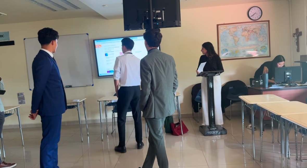 Delegados de pie frente a la pantalla del comité